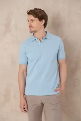 Remera celeste de algodón con cuello polo, manga corta y tapeta con botones. Diseño pigmentado en bajo cuello y cartera.