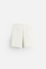 Bermuda color beige de corte recto, con cintura elástica ajustable con cordón, detalle de pliegues frontales, bolsillos laterales y bolsillos de vivo en la espalda.
