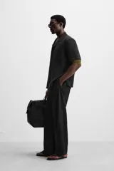 Camisa negra de corte relaxed fit, confeccionada en tejido con mezcla de modal. Tiene cuello bowling, manga corta, bolsillo de parche en el pecho y cierre frontal con botones.