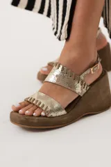 Sandalias de cuero color dorado con plataforma y taco de cuña forrado en gamuza marrón.