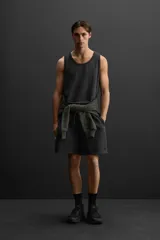 Bermuda jogger negra confeccionada en tejido de algodón con interior de rizo, cintura elástica ajustable con cordón y bolsillos laterales.