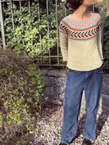 Sweater tejido a mano con hilo 100% algodón color beige, con cuello redondo y mangas largas. Presenta un diseño geométrico en el área del pecho en colores rosa, verde y marrón.