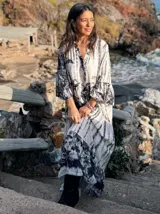 Vestido largo de estilo campesino con estampado de palmeras en tonos blanco y negro, con escote en V y mangas largas abullonadas.