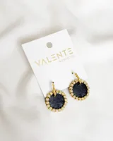 Par de aros colgantes con forma circular, con centro de tela color negro y borde con strass plateado. El aro es de metal dorado.