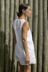 Vestido corto blanco con estampado de flores y diseño geométrico, sin mangas y con terminaciones onduladas en cuello y ruedo.