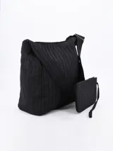 Bandolera negra con textura plisada y correa de hombro ajustable. Incluye un monedero pequeño con cierre.