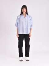 Camisa celeste con cuello mao, corte holgado, mangas 3/4 abullonadas con puños elásticos y cierre frontal con botones.