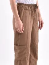 Pantalón marrón de corte ancho, con cintura elástica ajustable con cordón, bolsillos laterales y bolsillos tipo cargo en los muslos.