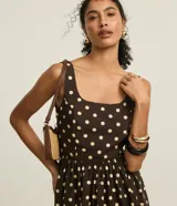 Vestido midi evasé de tricolina color marrón con lunares blancos, breteles anchos y escote cuadrado. Presenta lastex en la espalda y recorte fruncido en la cintura.