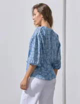 Blusa celeste con estampado floral blanco, escote en V y botones. Mangas 3/4 abullonadas con terminación elastizada.