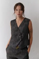 Chaleco grafito con cuello en V, cierre frontal con botones y bolsillos ribeteados.