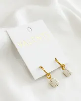 Aros colgantes con argolla dorada y dije de piedra blanca con vetas marrones.
