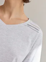 Remera gris claro de algodón con escote en V y bordados dorados y azul marino en los hombros.