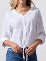 Blusa de algodón a rayas verticales finas en tonos blanco y lila, con escote en V, abertura frontal con botones y mangas largas regulables con presilla y botón. El ruedo termina anudado al frente.