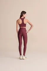 Top deportivo color bordó con corte asimétrico en el frente, diseño de impacto medio y relleno extraíble.