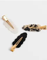 Set de tres hebillas para el pelo con forma ondulada. Incluye una hebilla blanca nacarada, una hebilla carey y una hebilla negra.