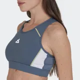 Top deportivo Le Coq Sportif color azul grisáceo con detalles en amarillo pálido y blanco. Presenta un diseño de espalda tipo nadador con tul elástico y costuras en contraste. Logo de la marca en amarillo en el pecho.