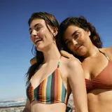 Top de bikini con estampado de rayas verticales en tonos marrón, verde, naranja y rosa. Diseño de triángulo con tirantes finos y detalle fruncido en el centro del busto.