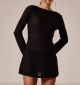 Minivestido blanco de tejido de punto calado, con espalda descubierta y lazos finos ajustables en la nuca. De manga larga y corte holgado.