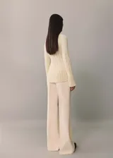 Sweater de punto color crema con cuello perkins y diseño de canalé vertical con aberturas.