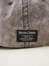 Gorra de gabardina color gris oscuro con visera curva y etiqueta con logo de la marca en el lateral.