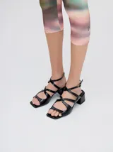 Sandalias de cuero charol color borgoña con tiras finas, taco cuadrado bajo y cierre con hebilla en el tobillo. Interior con estampado del logo de la marca en color naranja.