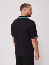 Chomba negra de corte regular, con cuello y mangas con rayas en contraste color verde y amarillo.