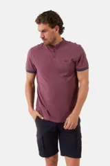 Remera de manga corta color azul grisáceo con cuello mao y tapeta de botones. Los puños de las mangas y el cuello son de color azul marino contrastante. Presenta un pequeño logo bordado en el pecho.