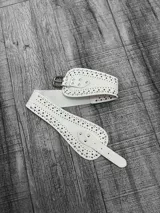 Faja blanca elástica con apliques de tachas plateadas y hebilla metálica.