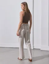 Pantalón de lino color beige con rayas verticales marrones, pretina ancha con punto smock y lazo ajustable, bolsillos verticales delanteros y bolsillos aplicados traseros.