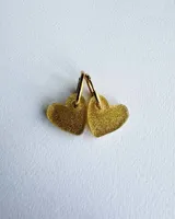 Par de aros colgantes dorados con dije en forma de corazón con glitter dorado.