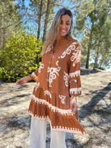 Vestido corto color marrón con estampado floral blanco, cuello mao y mangas 3/4 acampanadas.