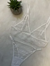 Conjunto de lencería blanco de encaje elastizado, compuesto por un corpiño triangular con breteles regulables, una tanga regulable con portaligas y ligas incluidas.