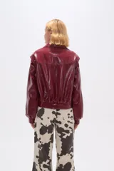 Chaqueta de eco-cuero color bordó, holgada, con cierre frontal, cuello tipo camisa y bolsillos laterales.