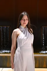 Mono largo color celeste, con escote halter cruzado, corte ajustado en la cintura y detalle de flecos largos en los laterales.