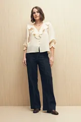 Camisa blanca a rayas verticales, con escote en V, mangas 3/4 con puños elastizados y volados.