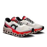 Championes de running On Cloudmonster 2, color blanco con detalles en negro, rojo y rosa.