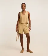 Bermuda femenina de corte recto y cintura alta, color beige, confeccionada en viscosa twill. Presenta abertura lateral por cremallera y ruedo plegado hacia afuera.