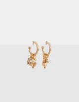 Aros dorados tipo argolla con dijes colgantes de herradura, trébol y cristal.