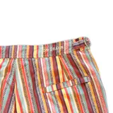 Short de baño con estampado de rayas horizontales y motivos geométricos en tonos naranja, marrón y blanco. Cuenta con pretina elástica y cordón ajustable.