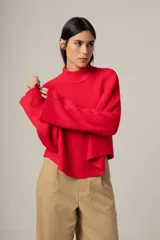Sweater rojo de punto con cuello alto y mangas largas acampanadas.