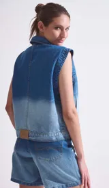 Chaleco de denim azul con degradé en blanco, cuello camisero y cierre frontal con botones.