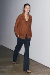 Blazer marrón de ante con cuello de solapa de muescas, manga larga, bolsillos de parche delanteros y cierre frontal con botones.
