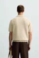 Polo color beige de punto con cuello solapa y manga corta.