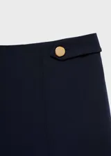 Pantalón azul marino de tiro medio y corte recto, con detalle de botones decorativos en la cintura y cierre frontal con botón, gancho y cremallera. Diseño crop.