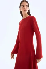 Vestido midi rojo de manga larga, con escote redondo y corte evasé con nesgas laterales para dar volumen.
