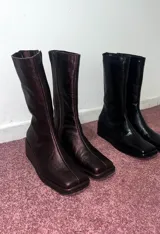 Bota de cuero negra, de caña media, punta cuadrada y taco bajo forrado.