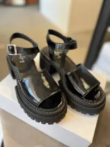 Sandalias negras de cuero charol con plataforma y correa al tobillo.