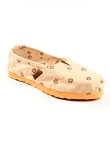 Alpargatas de lona color beige con estampado de flores marrones y suela de goma color naranja.