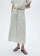 Falda midi de tiro alto con estampado de cuadros en tonos neutros. Presenta cierre lateral con cremallera, diseño evasé y costuras decorativas. Confeccionada en tejido ligero de algodón.